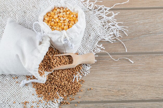 A white sack full of corn grains on a gray background.