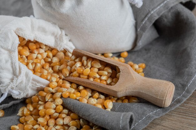 A white sack full of corn grains on a gray surface.