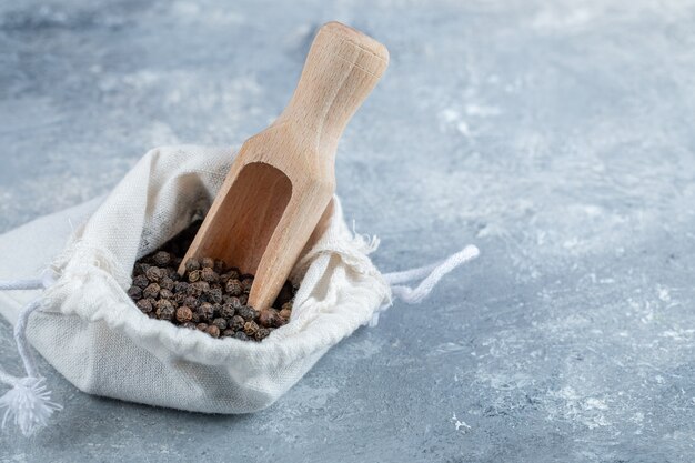 A white sack full of dried pepper on a gray background. 