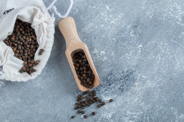 A white sack full of dried pepper on a gray background. 