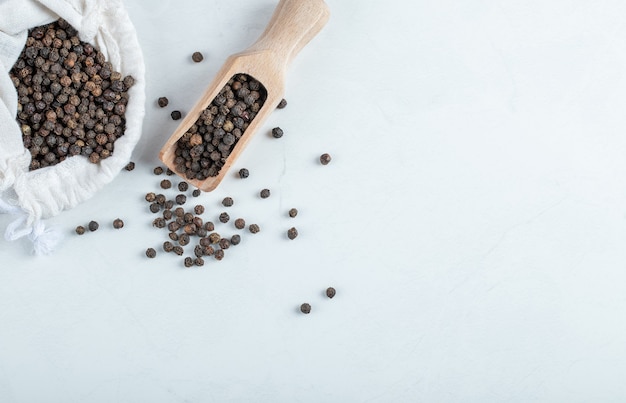 A white sack full of dried pepper on a gray background. 