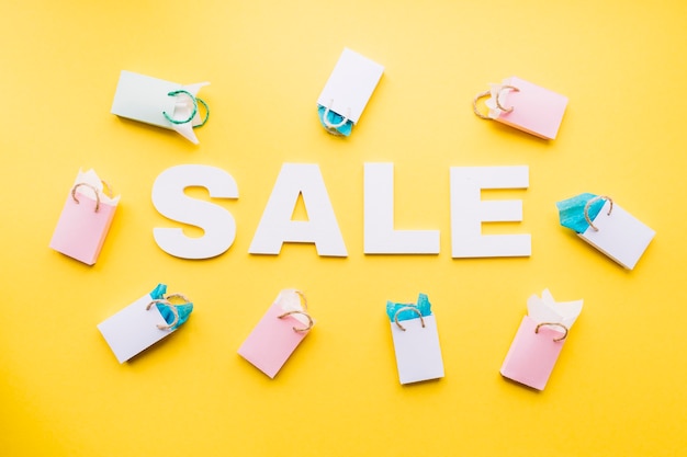 White sale text surrounded with small shopping bags on yellow background