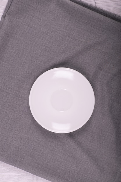 Белая тарелка с серой скатертью