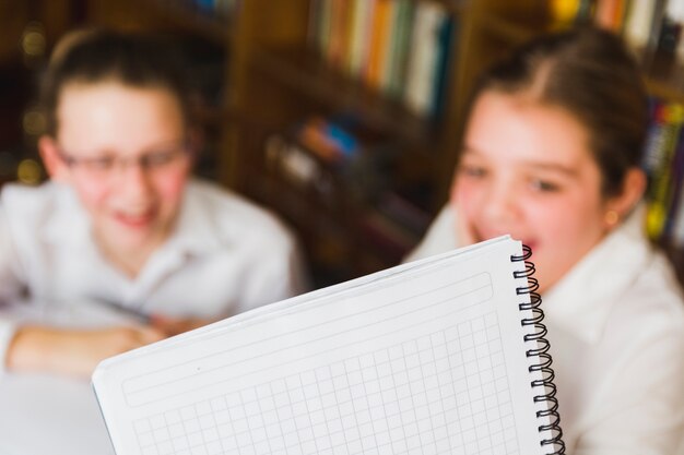 Бесплатное фото Белая школьная тетрадь и смеющиеся маленькие девочки