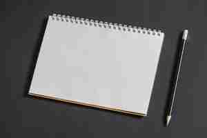 Free photo white scrapbook and pencil on grey background