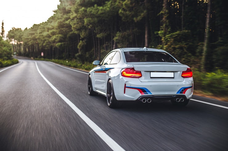 Free Photo white sedan driving on the highway accross the forest