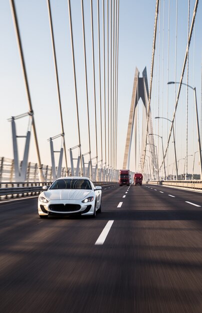 A white sedan sport car driving on the bridge.