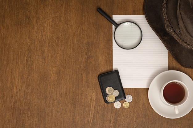 White sheet, money, magnifier and coffee on wooden table, flat lay, travel concept.