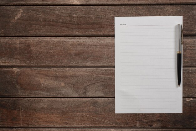 White sheet over wooden table with a pen