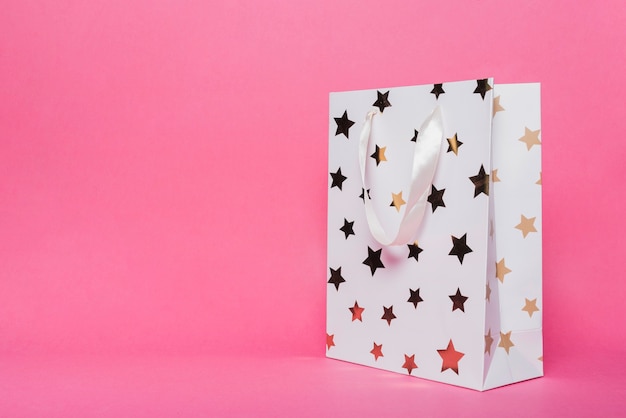 White shopping bag with star shape pattern on pink background