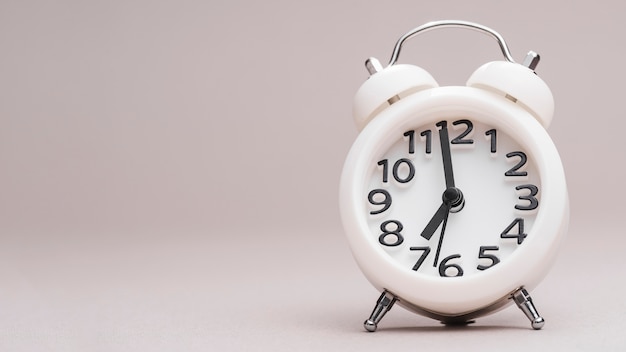 White small alarm clock against colored background