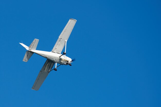 White small plane, rusted on bottom, making a turn in the sky in San Diego