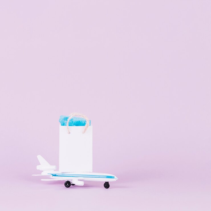 Free Photo white small shopping bag over toy airplane against pink background
