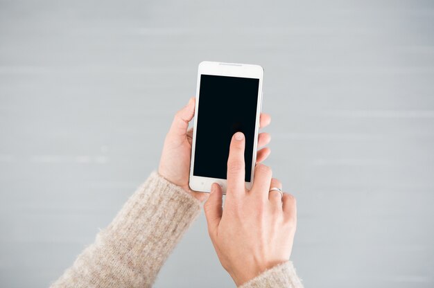 white smartphone in female hands on a gray background