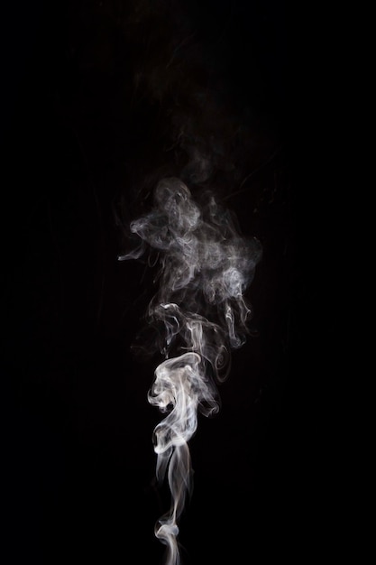 White smoke raising on black background with copy space