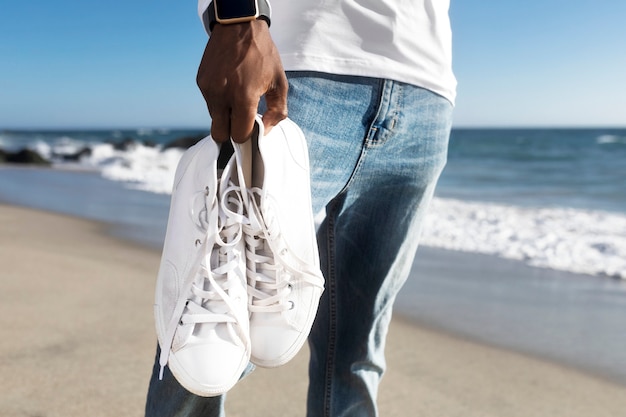 Free photo white sneakers closeup men’s apparel summer fashion beach photoshoot