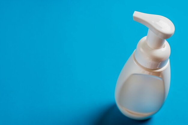 White soap dispenser bottle on blue backdrop