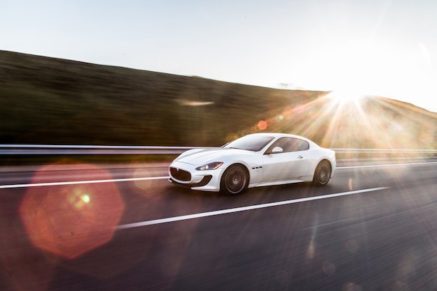 A white sport car driving in the highway.