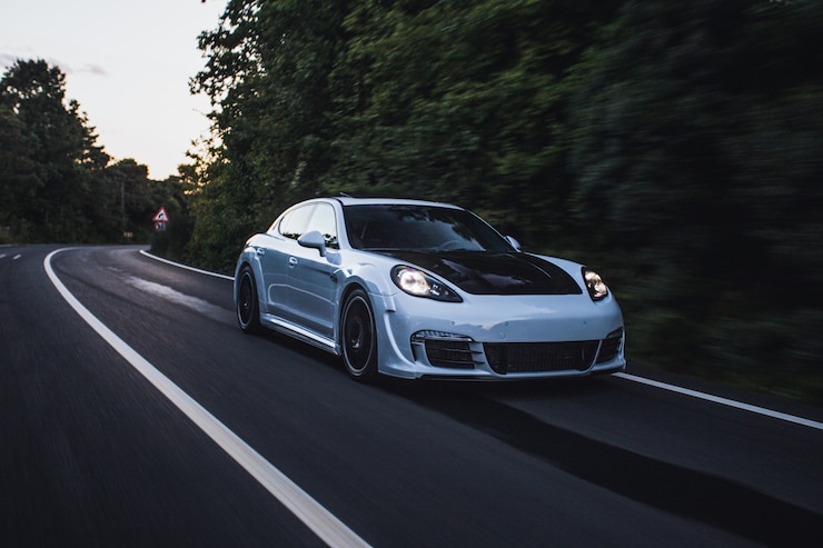 ฟรี Photo a white sport car with black autotuning driving by the forest.