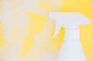 Free photo white spray bottle against soap sud over yellow backdrop