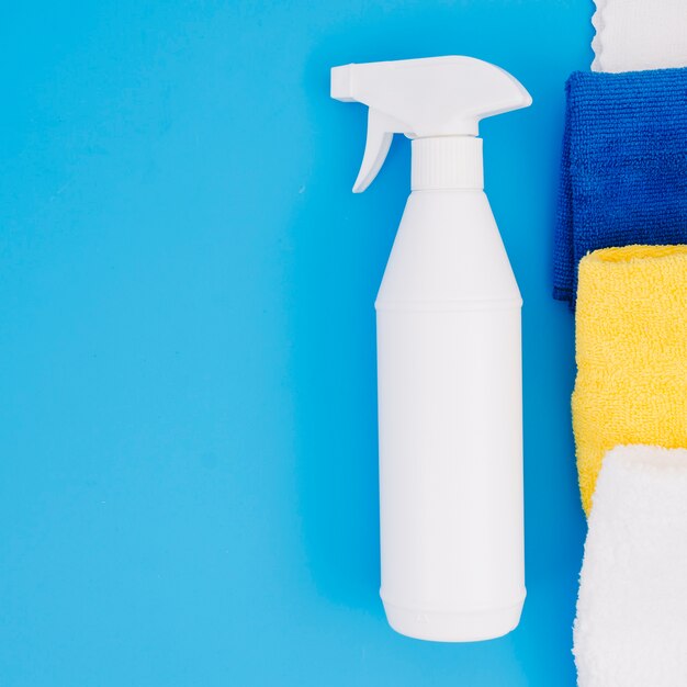 White spray bottle near the colorful folded napkin on blue background