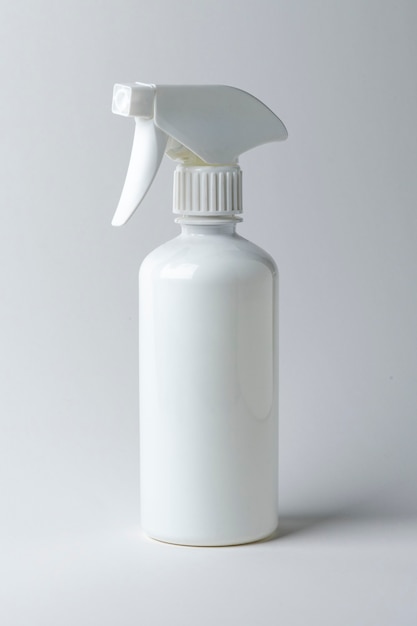 Белая бутылка с распылителем на простом фоне
