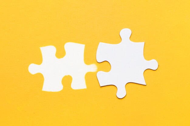 White stamp of puzzle piece with cardboard puzzle piece on yellow surface