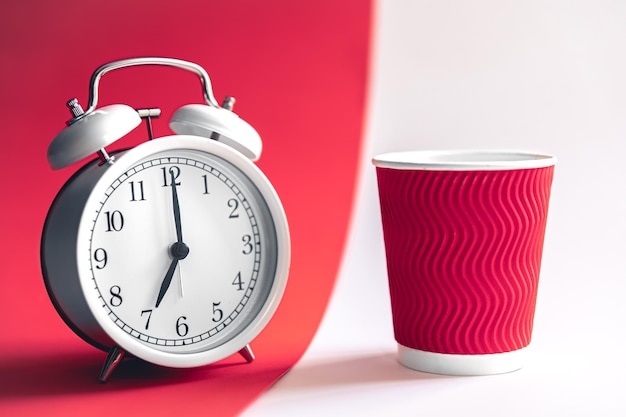 White stylish alarm clock and paper cup morning concept
