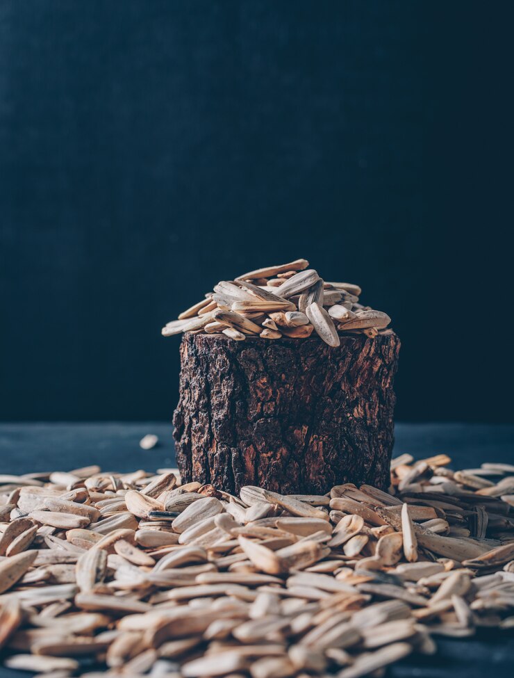 मुफ़्त फोटो white sunflower seeds in a wood stub and around on a black background. side view. space for text