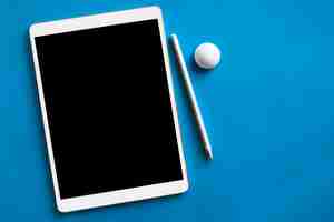 Free photo white tablet and pencil on blue surface