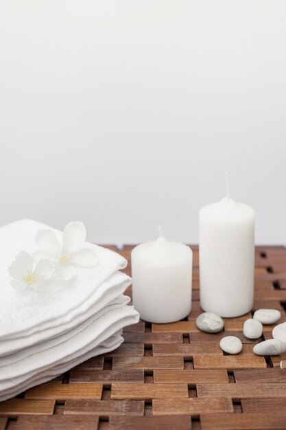White towel; flowers; candles and pebbles on wooden surface