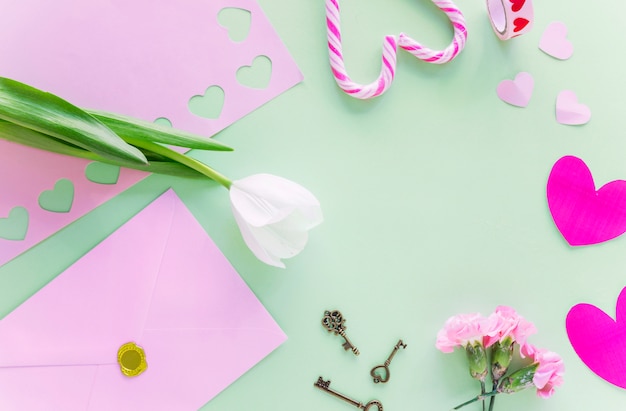 White tulip with paper hearts on table 