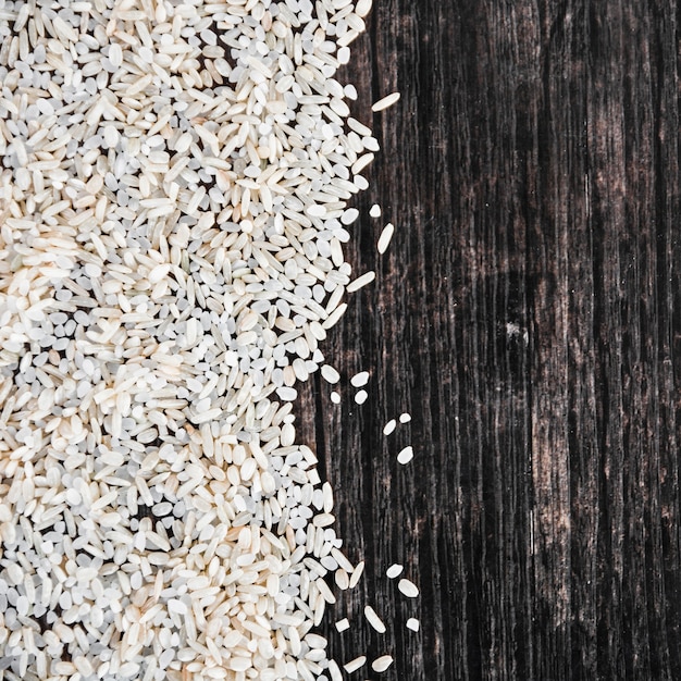 White uncooked rice spread on wooden backdrop