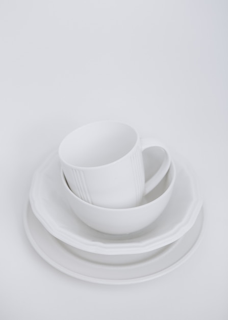 белая утварь три пластины и чашка на белом фоне