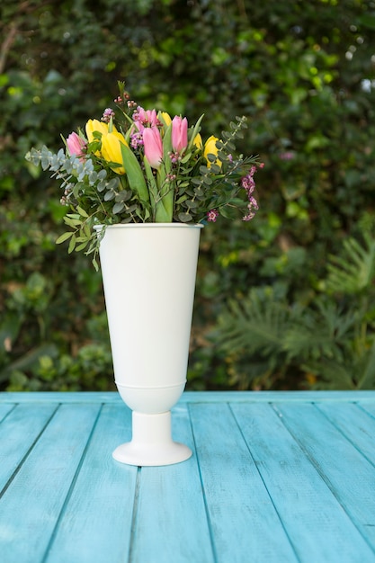 White vase with colored flowers outdoors