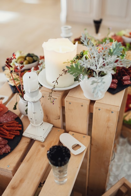 White vases with greenery stand on the wooden boxes