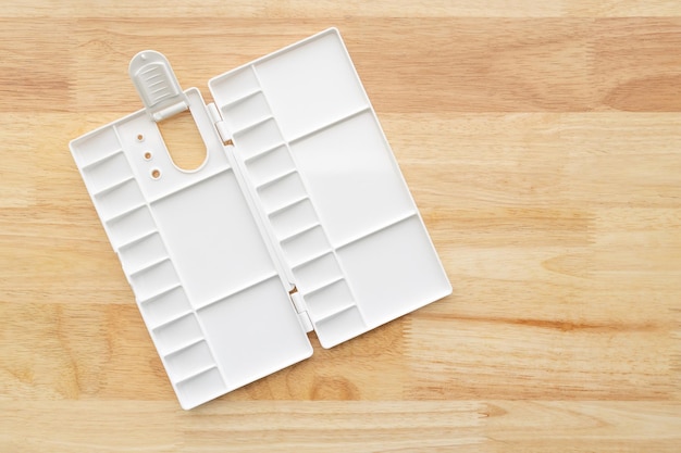 White watercolor palette. empty watercolor tray isolated on wood background. white plastic paint palette.