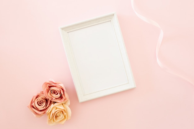 white wedding frame with roses on a pink background