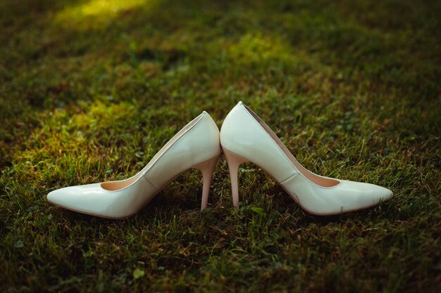 White wedding shoes stand back to back on green grass