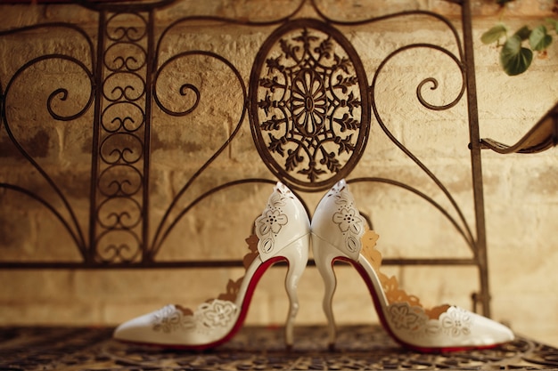 Le scarpe da sposa bianche stanno fianco a fianco sulla panchina d'acciaio