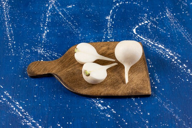 White whole and sliced fresh turnips on wooden board