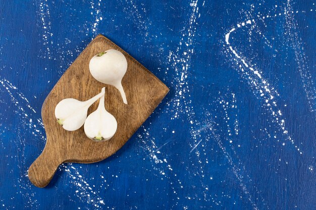 White whole and sliced fresh turnips on wooden board