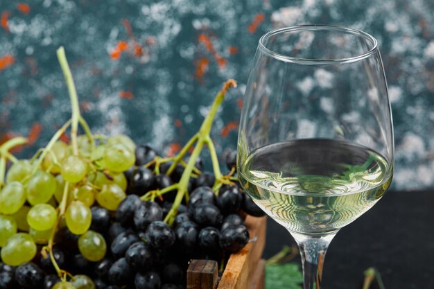 White wine in a glass with a bunch of green grapes around. 