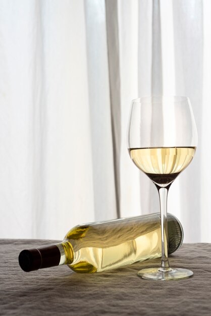 White wine glass with fallen bottle on table