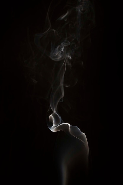 White wispy smoke swirls on black background