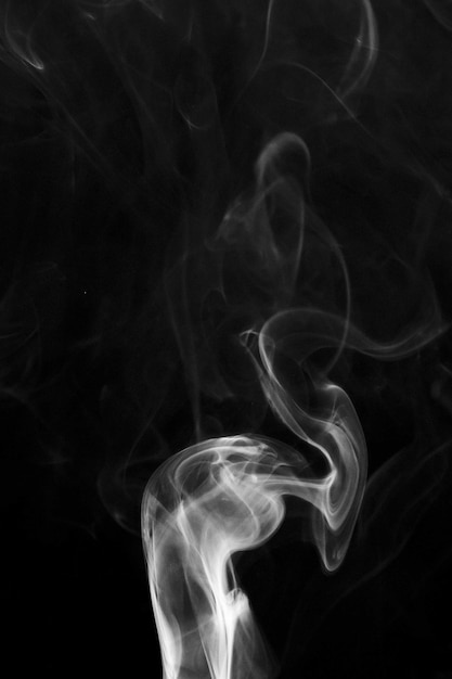 White wispy smoke swirls on black background