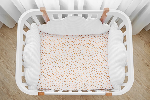 枕の形をした白い木製のベビーベッドは、赤ちゃんの部屋に雲の形をしています。子供のベッドの上面図 Premium写真