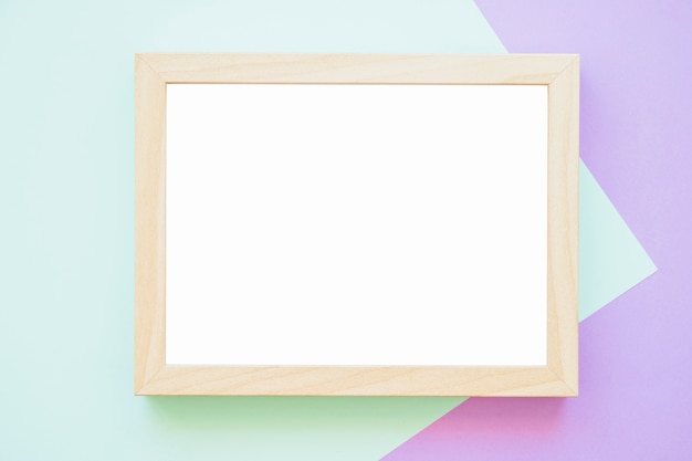 Белая деревянная рамка на зеленом и фиолетовом фоне