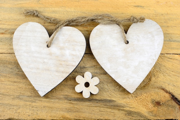 Белые деревянные сердца и цветок на деревянной поверхности