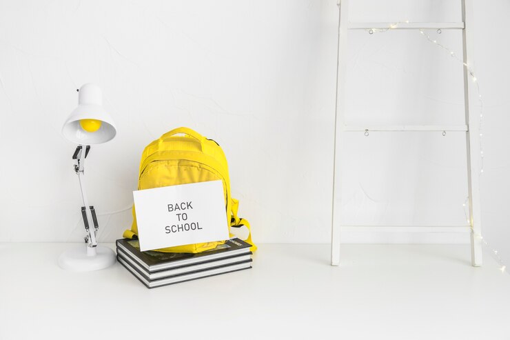 Free Photo white workspace for pupil with yellow backpack 
